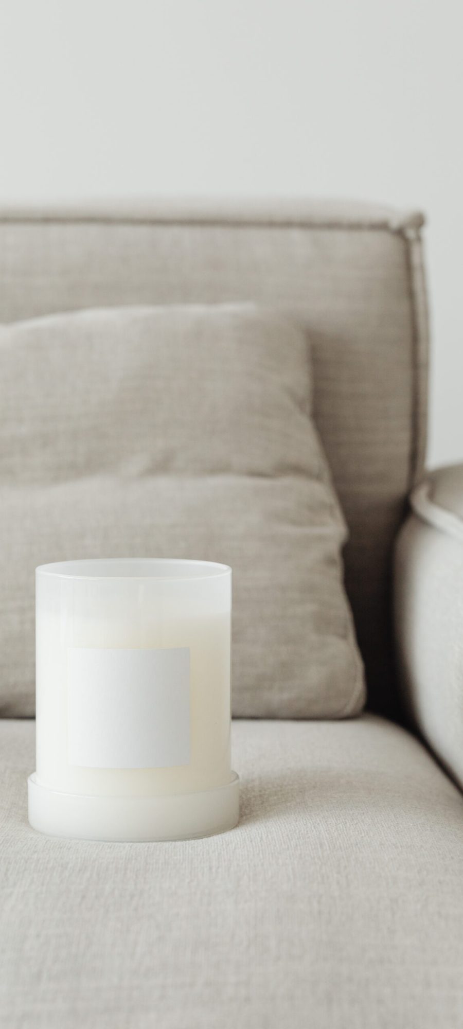 kaboompics_candle-in-white-glass-with-label-on-linen-couch-27062